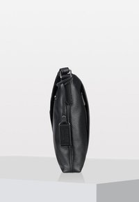 Schwarze Lederhandtasche mit strukturierter Oberfläche, schlankem Profil und verstellbarem Träger. Mit einem kleinen Etikett-Detail und einem Reißverschlussverschluss.