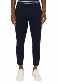 Granatowe spodnie chino z bawełny o zwężanym kroju, z przednimi kieszeniami oraz zapięciem na guzik i zamek błyskawiczny. W połączeniu z białymi sneakersami.