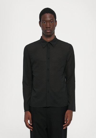 Camicia nera a maniche lunghe con un sottile motivo a pois bianchi, colletto a punta, bottoni frontali e una vestibilità su misura. Costruzione senza cuciture.