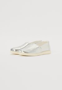 Silberne Slipper mit glatter Metallic-Oberfläche, ausgestattet mit einem niedrigen Profil und einer kontrastierenden weißen Sohle. Minimalistisches Design mit Nahtdetails.