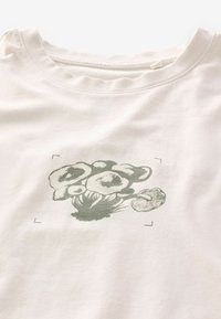 Krémové bavlněné tričko s potiskem zelené květinové grafiky. Kulatý výstřih s mírným strečem a jemnou strukturou; jednoduchý design, bez ozdob.