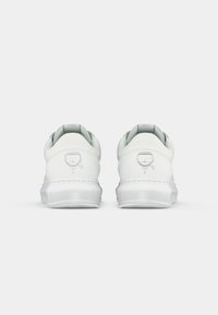 Balties sportbačiai su lygiu odiniu viršumi, paminkštintu apykakle, permatomu padu ir logotipu išspaustu ant kulno. Minimalistinis dizainas.