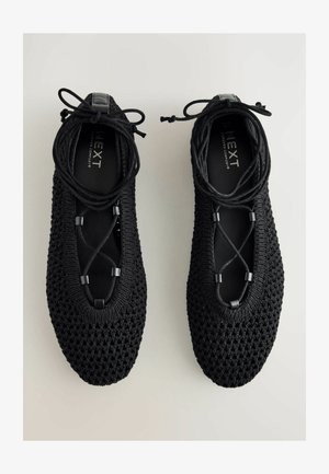 Scarpe in maglia nera con un motivo testurizzato, dotate di un design leggero, chiusura con lacci e punta arrotondata.