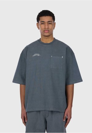 T-shirt en coton gris surdimensionné avec un col rond, des manches courtes, une poche poitrine et du texte brodé blanc à l'avant.