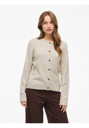 Gilet beige côtelé à manches longues, décolleté rond et cinq boutons marron sur le devant ; associé à un pantalon marron foncé.