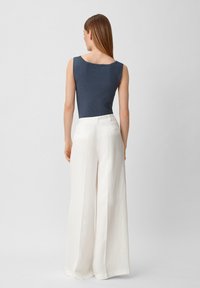Granatowy prążkowany tank top połączony z białymi, szerokimi spodniami o wysokim stanie. Strój charakteryzuje się minimalistycznym designem i luźnym krojem.