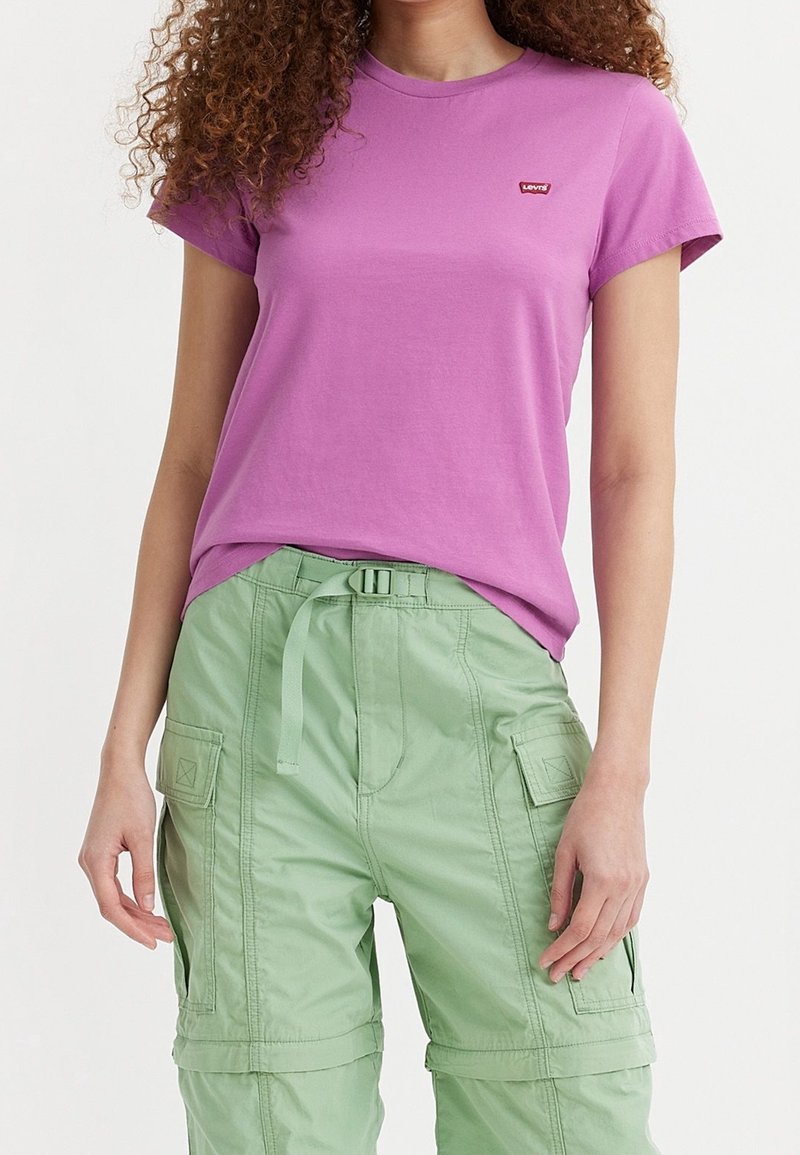 Rosa T-shirt med kort ärm och rund halsringning samt liten röd Levi's-logga, som är ihop med gröna cargobyxor med fickor och justerbart bälte.