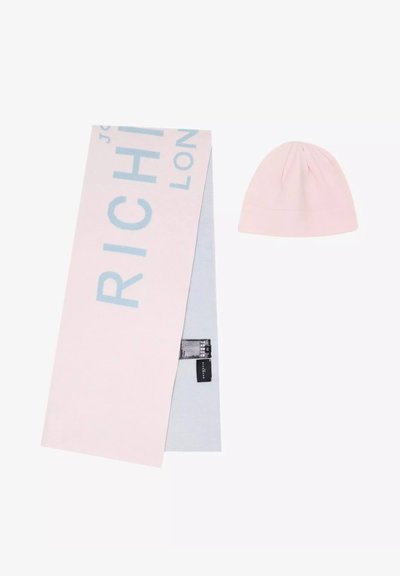 Cappello e sciarpa lavorati a maglia di colore rosa chiaro. La sciarpa presenta la scritta "RICH" in testo blu, con una texture morbida. La sciarpa è parzialmente ripiegata, mostrando una fodera grigia.