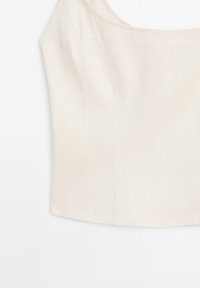 Haut sans manches beige clair à coupe droite, fabriqué dans un tissu lisse. Présente des détails discrets de coutures pour un look ajusté.