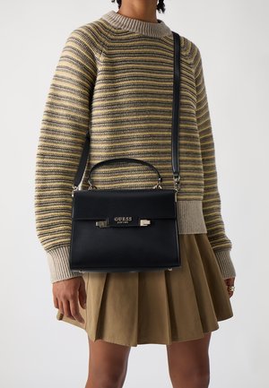 Musta nahkainen käsilaukku, jossa on jämäkkä muoto, kultaiset yksityiskohdat ja yläkahva. Laukussa on irrotettava olkahihna ja lukollinen suljin.