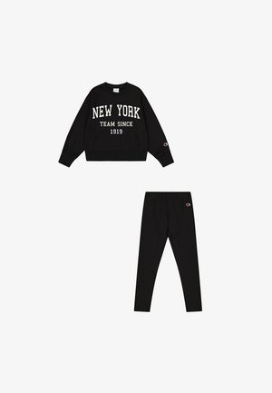 Felpa nera con la scritta "NEW YORK TEAM SINCE 1919" in bianco, abbinata a legging neri. Entrambi gli articoli presentano sottili dettagli del logo.
