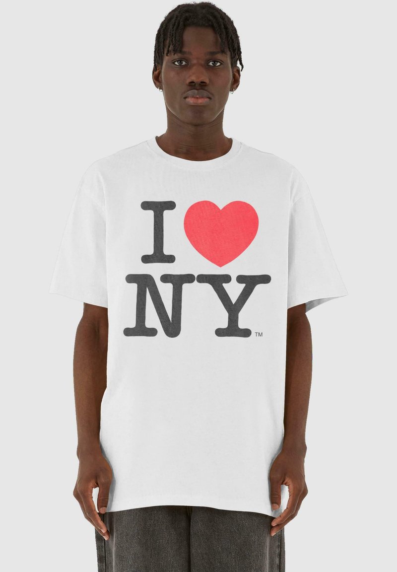 Hvid bomulds t-shirt med et dristigt "I ♥ NY" print i store sorte og røde bogstaver. Kortærmet og med en afslappet pasform.