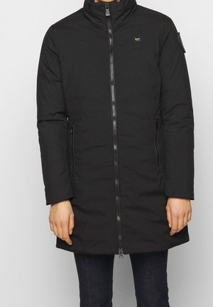 Schwarzer, knielanger, isolierter Wintermantel mit hohem Kragen, Frontreißverschluss, Seitentaschen und aufgesetzten Details an Brust und Arm.