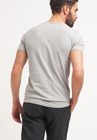 Tricou din bumbac gri, cu mâneci scurte, decolteu rotund și o siluetă ajustată. Textură netedă, design curat și fără grafica vizibilă.