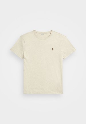 Beige bomull t-shirt med rund hals och korta ärmar. Har en liten brun logotyp på vänster bröst. Mjuk textur, avslappnad design.
