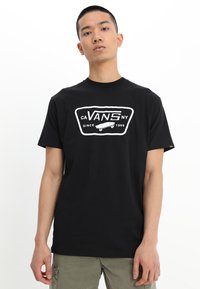 Svart bomullströja med vitt Vans-logotyp och skateboardgrafik. Klassisk rund hals och korta ärmar, med en avslappnad passform.