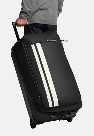 Borsa da viaggio nera con ruote e texture liscia, caratterizzata da tre strisce verticali bianche e una chiusura a zip; manico robusto e ruote visibili.
