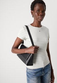 Gestreept lichtgroen T-shirt met ronde hals en korte mouwen, gecombineerd met een zwarte leren schoudertas met een strak design.