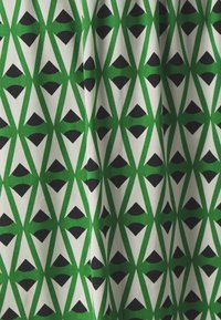 Tissu présentant un motif géométrique répétitif de triangles verts et de formes noires sur un fond blanc, mettant en avant une texture de tissu lisse.