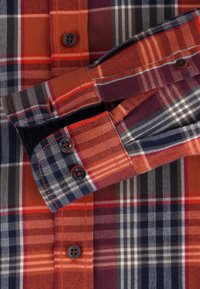 Camicia a quadri rossa e blu navy con colletto a bottoni, polsini a doppio bottone e motivi a scacchi vari su un tessuto morbido.