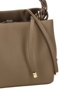 Bolso de cuero marrón con textura granulada, presenta un adorno de herrajes dorados y una correa trenzada. El bolso tiene una apertura espaciosa con un diseño minimalista.