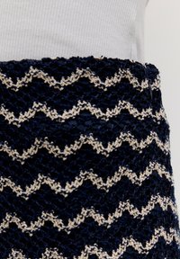 Kanten rok met een marineblauw en crèmekleurig zigzagpatroon, voorzien van een gestructureerde oppervlakte en een aansluitende tailleband.