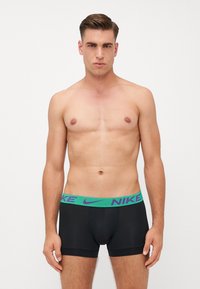 Črne moške bokserice z teksturiranim zelenim in vijoličnim pasom Nike, ki imajo prilega fit in mehko material. Brez vzorcev ali dodatkov.