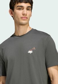 Šedé bavlněné tričko s malým grafickým obrázkem šálku se smetanou a čokoládou umístěným na levém prsu. Kulatý výstřih a krátké rukávy.