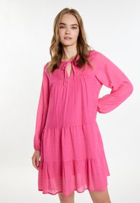 Roze haljinska haljina s dugim rukavima i izrezom u obliku ključa. Izrađena od teksturirane tkanine s suptilnim prugastim uzorkom.