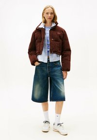 Brun kordfløjl cropped jakke med knaplukning, blåstribet skjorte under, brede denim shorts, hvide sneakers og hvide sokker.