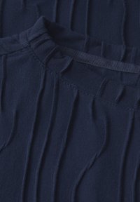 Tejido de color azul marino con textura, que presenta estrías verticales y cinturilla fruncida. Mezcla de algodón suave con una superficie lisa y un brillo sutil.