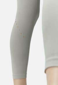 Leggings atletici grigi con texture a coste, design aderente e ritagli decorativi lungo la parte inferiore della gamba. L'orlo è a risvolto.