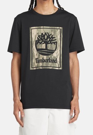 Zwart katoenen T-shirt met een groot boomlogo in zwart en groen op een gedempte achtergrond, met korte mouwen en een losse pasvorm.