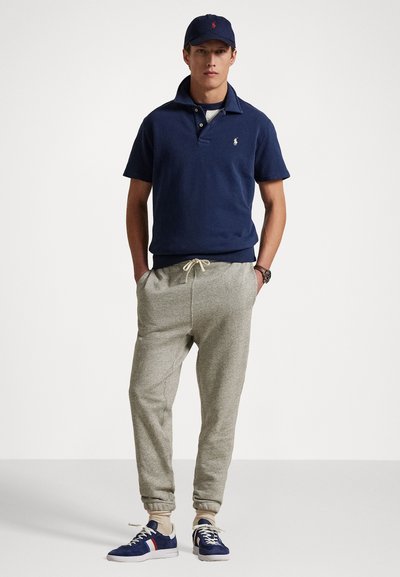 Navy polo shirt with a collar, gray sweatpants with elastic cuffs, and blue sneakers with red and white accents. Casual athletic look.