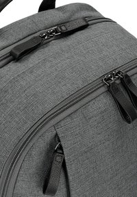 Un sac à dos en tissu gris avec une surface texturée, doté de doubles zips avec des tirettes en cuir noir et un design épuré et moderne.