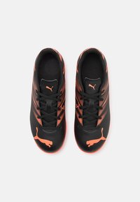 Zapatillas deportivas negras con toques naranjas. Presenta un upper texturizado, cordones y un prominente logo de Puma. Punta redondeada y suela acolchada.