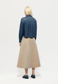 Blue denim cropped jacket with long sleeves, paired with a beige satin maxi skirt. The skirt has a smooth texture and a hemline detail.