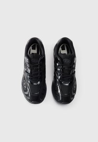 Schwarze Sportschuhe mit Mesh- und glänzenden Akzenten; verfügen über eine runde Zehenform, Schnürdesign und strukturiere Sohle. Die Aufsicht zeigt ein symmetrisches Layout.