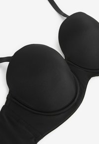 Svart bh med underwire, släta vadderade kupor och justerbara axelband. Sömlös design med en mjuk textur och en minimalistisk utseende.