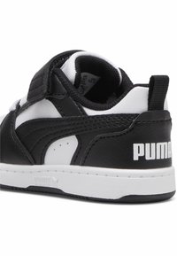 Svart og hvit skinnidrettssko med borrelåsrem, polstret krage, teksturert detaljering, og synlig Puma-logo på hælen.