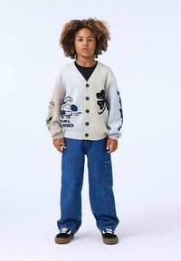 Ljusgrå cardigan med svarta knappar, prydd med färgglada broderade motiv; kombinerad med lös blåjeans och svarta sneakers.