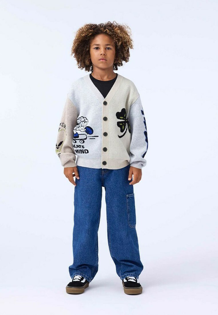 Ljusgrå cardigan med svarta knappar, prydd med färgglada broderade motiv; kombinerad med lös blåjeans och svarta sneakers.