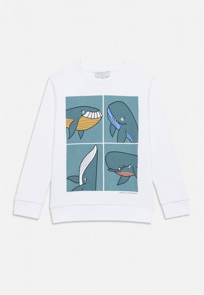 Balta džemperis ar četriem karikatūru haizivju attēlojumiem zilās kvadrātos priekšpusē, katrs haizivs rāda atšķirīgu izteiksmi.