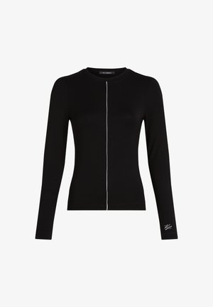 Zwarte langemouwen top van zacht materiaal, met een centrale witte stiklijn en een klein logo geborduurd op de onderkant van de mouw.