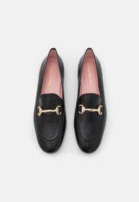 Mustad nahast loaferid ümarate ninadega, millel on kuldne riistvaraline aksessuaar. Pehmed roosad sisetallad brändingu sümboliga sees. Sile tekstuur.