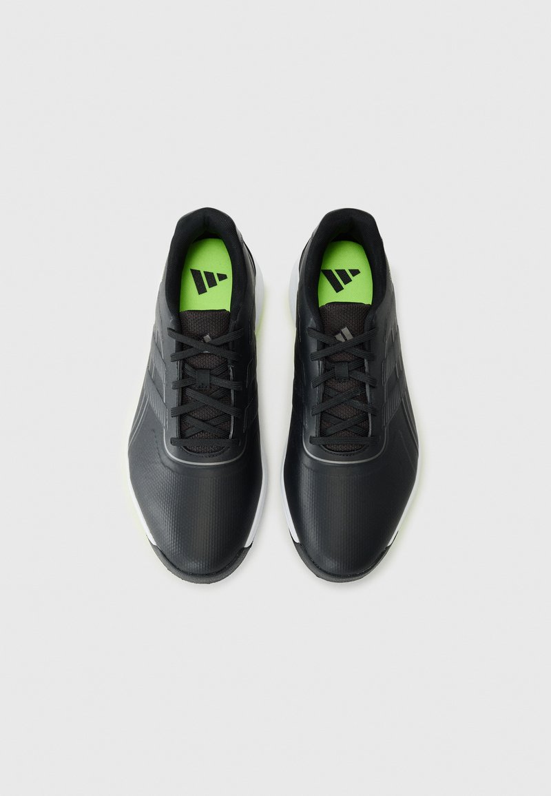 Schwarze Sportschuhe mit strukturiertem Obermaterial, grünen Innensohlen und drei weißen Streifen an der Seite. Gepolstertes und schnürbares Design.