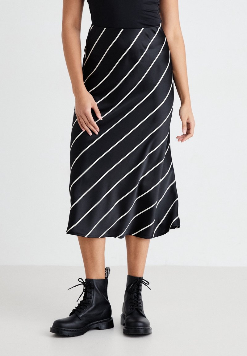 Musta satiininen midihame valkoisilla diagonaaliraidoilla, hieman kellotettuhelmainen, yhdistetty mustiin nyörillä varustettuihin maihinnousukenkiin.