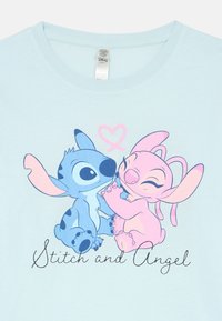  personagens de desenho animado Stitch e Angel, em azul e rosa, sentados e tocando os narizes, com um coração rosa acima deles.
