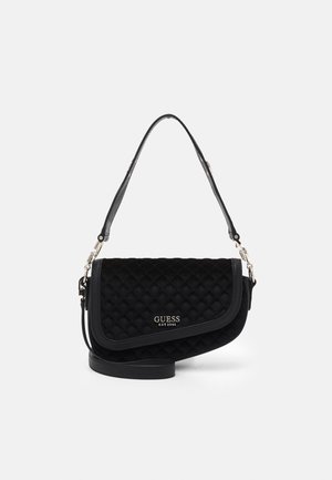 Czarna pikowana torebka na ramię z klapką, srebrnymi okuciami i logo "GUESS EST 1981" na przodzie, prezentowana na białym tle.