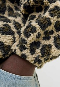 Fleece sweater med leopardprint i beige, mørkegrøn og sort. Struktureret stof og en løs pasform, kombineret med et denimliv.